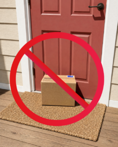A cardboard wine shipment sitting in direct sun on a front porch, marked with a "do not ship" symbol